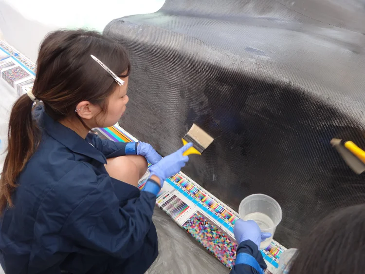 Team member applying resin to the carbon fiber shell